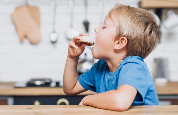 Seitenansichtjunge, der ein Plätzchen isst