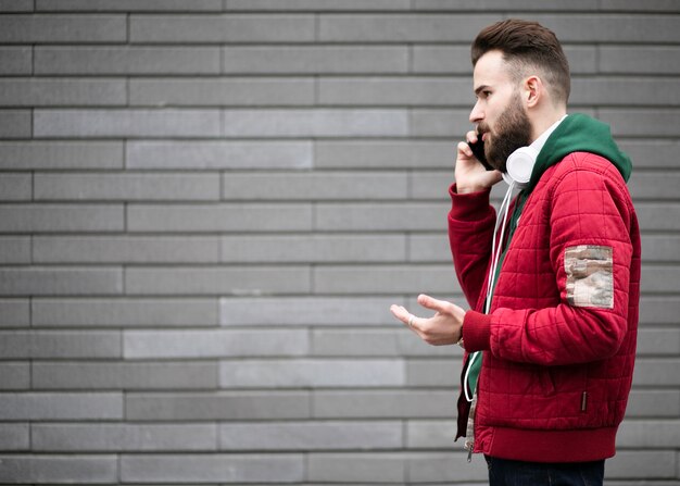 Seitenansichtkerl mit Kopfhörern sprechend am Telefon