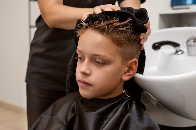 Kostenloses Foto seitenansichtkind, das haare im salon wäscht