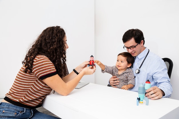 Seitenansichtkind, das mit einem Spielzeug am Besuch eines Doktors spielt