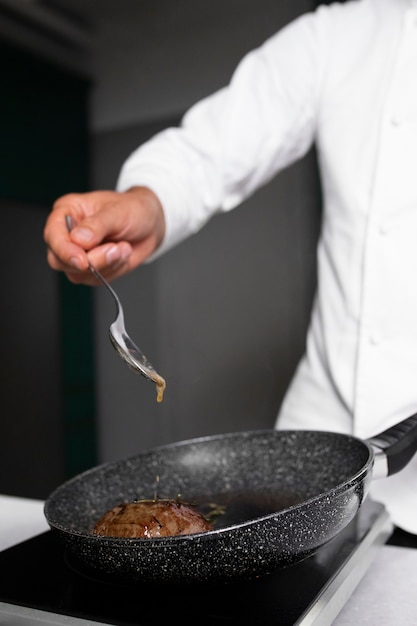 Kostenloses Foto seitenansichtkoch, der fleisch kocht