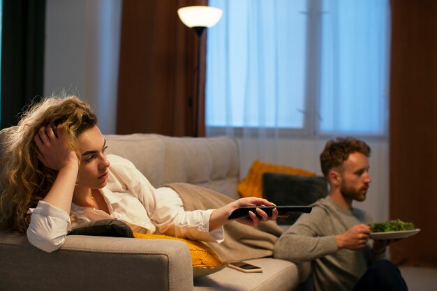 Seitenansichtleute, die essen und fernsehen