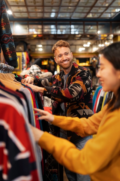 Seitenansichtleute, die Kleidung im Secondhand-Laden betrachten