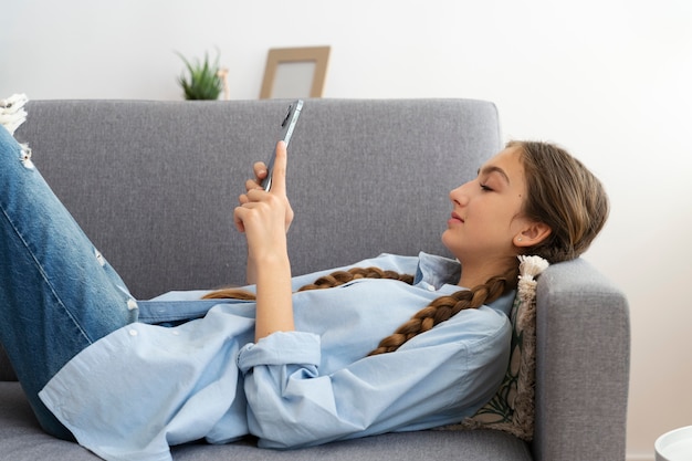 Seitenansichtmädchen auf Couch mit Smartphone