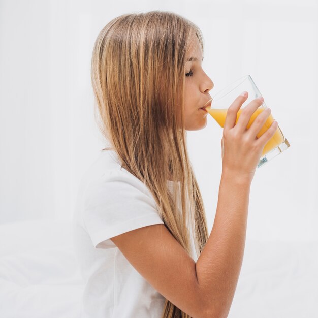 Seitenansichtmädchen, das Orangensaft trinkt