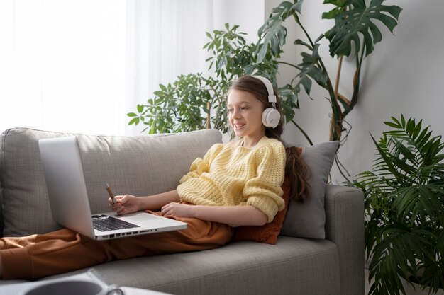Seitenansichtmädchen mit Laptop auf Couch