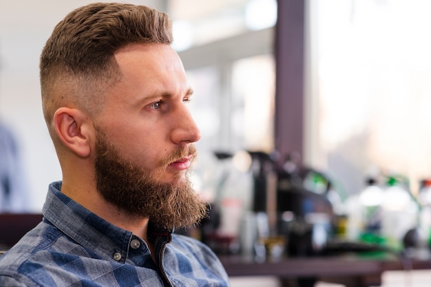 Kostenloses Foto seitenansichtmann, der auf einen haarschnitt wartet