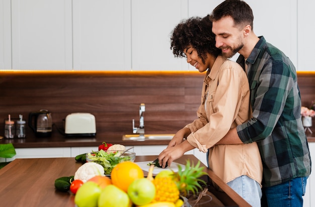 Seitenansichtmann, der das Frauenkochen umarmt