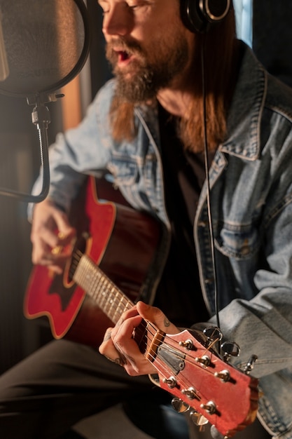 Seitenansichtmann, der die Gitarre im Studio spielt