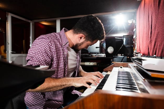 Seitenansichtmann, der die Tastatur im Studio spielt