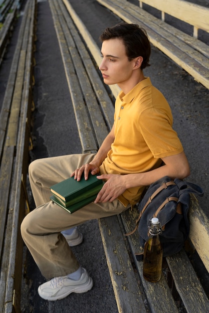 Kostenloses Foto seitenansichtmann, der draußen bücher hält