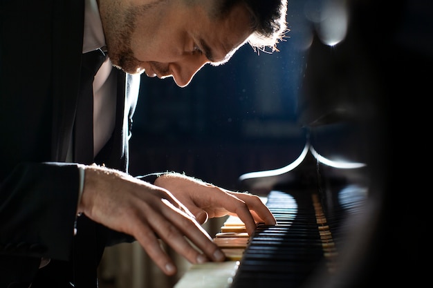 Kostenloses Foto seitenansichtmann, der klavier spielt