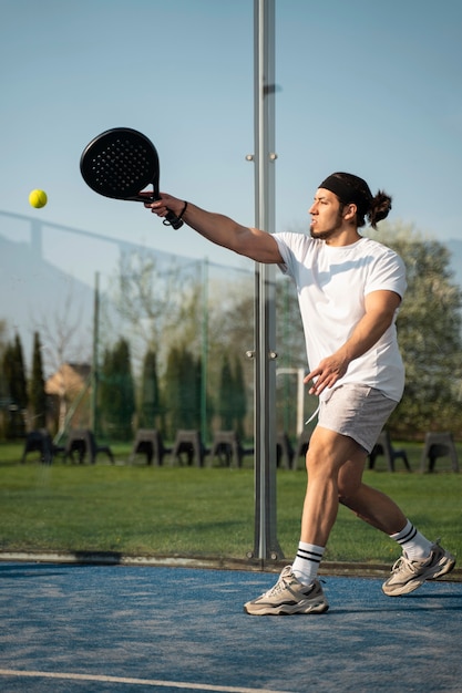 Seitenansichtmann, der Paddle-Tennis spielt