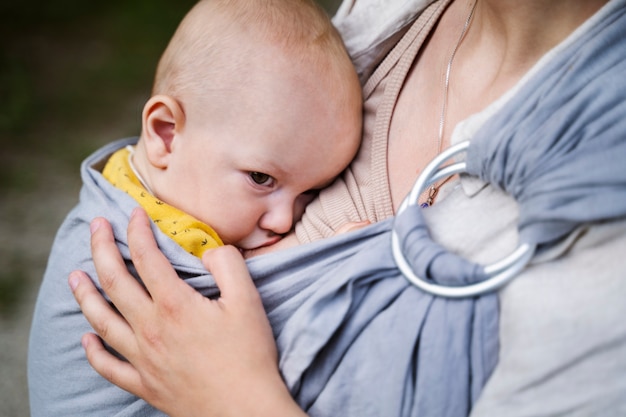 Kostenloses Foto seitenansichtmutter, die draußen baby hält