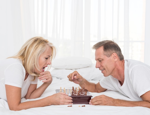 Seitenansichtpaare, die Schach im Schlafzimmer spielen