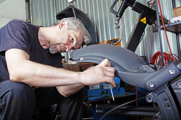 Seitenansichtporträt eines mannes, der in der garage arbeitet, motorrad repariert und anpasst