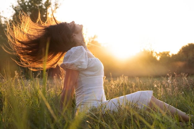 Kostenloses Foto seitenansichtsfrau, die auf gras sitzt