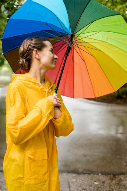 Seitenansichtsfrau, die einen bunten Regenschirm hält