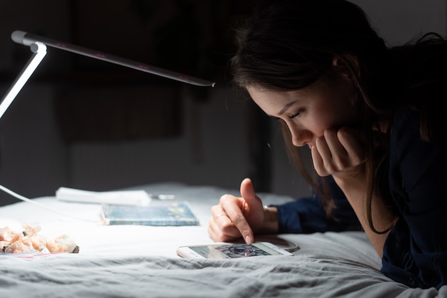 Seitenansichtsfrau, die im dunklen Schlafzimmer arbeitet.