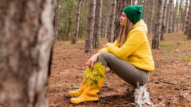 Seitenansichtsfrau, die im Wald sitzt