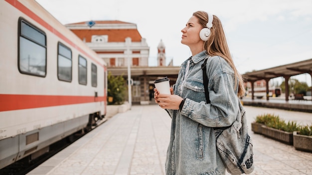 Seitenansichtsfrau, die Musik am Bahnsteig hört