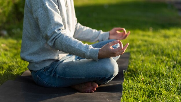 Seitenansichtsmann, der auf dem Gras meditiert
