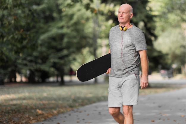 Seitenansichtsmann, der Skateboard hält