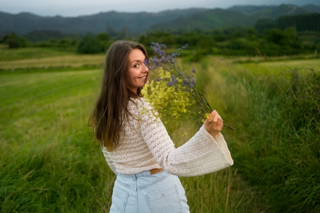 Kostenloses Foto seitenansichtsmileyfrau, die blumen hält