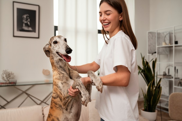 Kostenloses Foto seitenansichtsmileyfrau, die mit hund tanzt