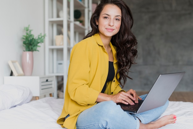 Seitenansichtsmileymädchen mit Laptop zuhause