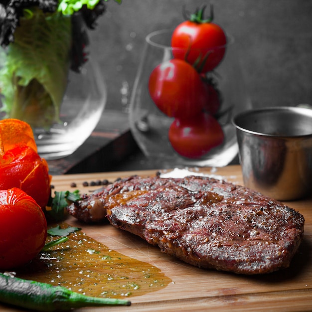 Seitenansichtssteak mit Tomate und Papier und würziger Sauce im Steakbrett