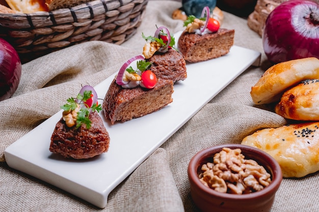 Seitenansichtstorte mit gebackenem Hackfleisch-Zwiebel-Tomaten-Grün und Walnüssen auf dem Tisch