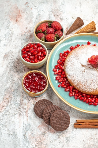 Seitennahaufnahme der appetitliche Kuchen der appetitliche Kuchen neben den Schalen mit Beerenplätzchen