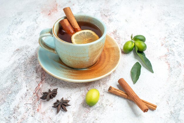 Seitennahaufnahme eine Tasse Tee eine Tasse Tee mit Zitrone und Zimt auf der Untertasse mit Zitrusfrüchten Sternanis und Zimtstangen auf dem Tisch