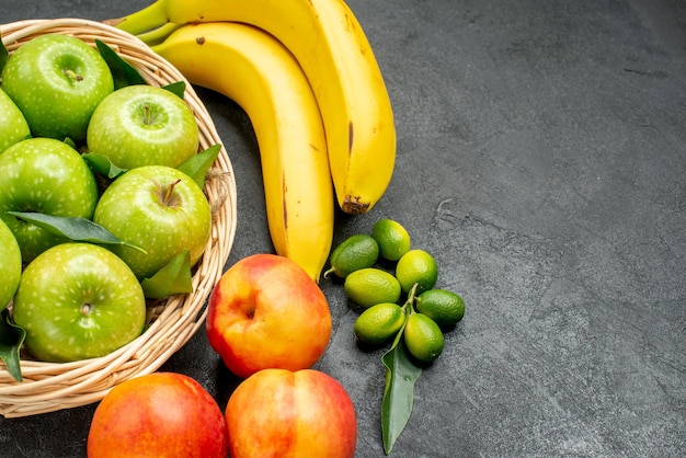 Seitennahaufnahme Früchte Bananen Äpfel im Korb Limetten Nektarinen auf dem Tisch