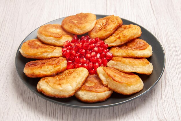 Seitennahaufnahme-Pfannkuchen appetitliche Pfannkuchen und Granatapfelkerne auf dem weißen Tisch