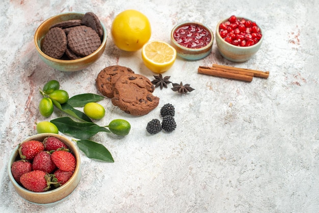 Seitennahaufnahme Schokoladenkekse Schokoladenkekse Schalen mit Erdbeeren Zitrusfrüchte Zimtstangen auf dem Tisch