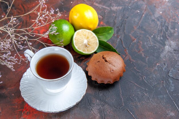 Seitennahaufnahme Zitrusfrüchte Cupcakes Limetten Zitronen mit Blättern eine Tasse Tee