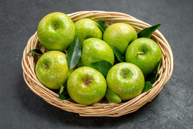 Seitennahaufnahmeäpfel im hölzernen Korb des Korbes von acht Äpfeln mit Blättern auf dem dunklen Tisch