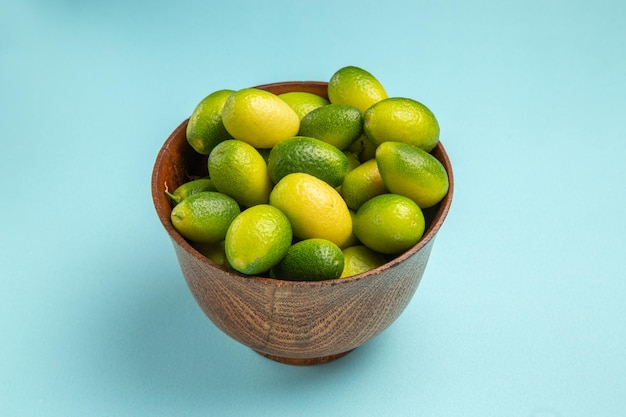 Seitennahaufnahmefruchtschale mit grünen Früchten auf der blauen Oberfläche