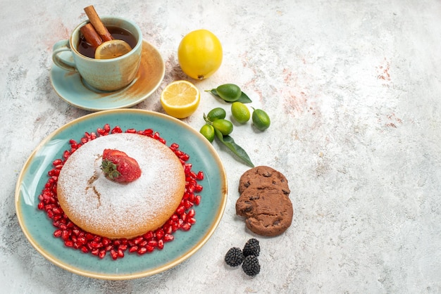 Seitennahaufnahmekuchen der appetitliche Kuchen mit Granatapfel-Zitrusfruchtkeksen auf dem Tisch