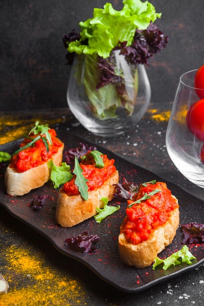 Seitensicht-Snack mit geschnittenem Brot von oben Tomatensalat und Rucola in dunklem Teller