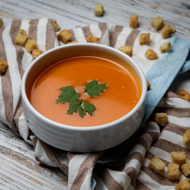 Seitensicht-Tomatensuppe mit Crackern und Servietten im weißen Teller auf Holztisch