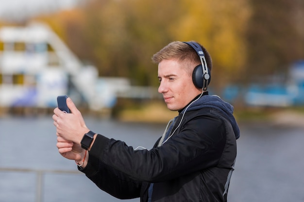 Seitlich blonder Mann, der draußen Musik hört