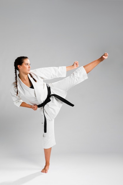 Seitlich Karatefrau im traditionellen weißen Kimono auf weißem Hintergrund