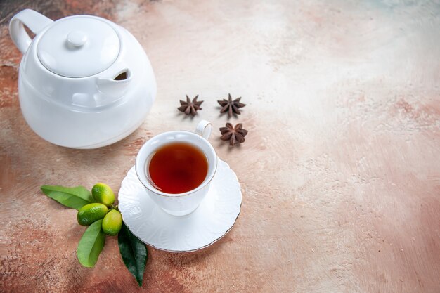 Seitliche Nahaufnahme eine Tasse Tee weiße Teekanne eine Tasse Tee Sternanis Zitrusfrüchte