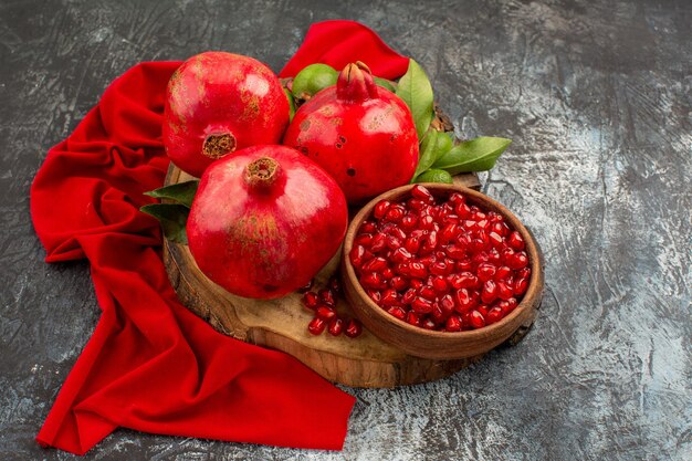 Seitliche Nahaufnahme Früchte rote Granatäpfel auf dem Schneidebrett auf der roten Tischdecke