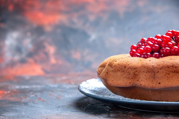 Seitliche Nahaufnahme leckerer grauer Teller mit Kuchen und roten Johannisbeeren auf dem rot-blauen Hintergrund