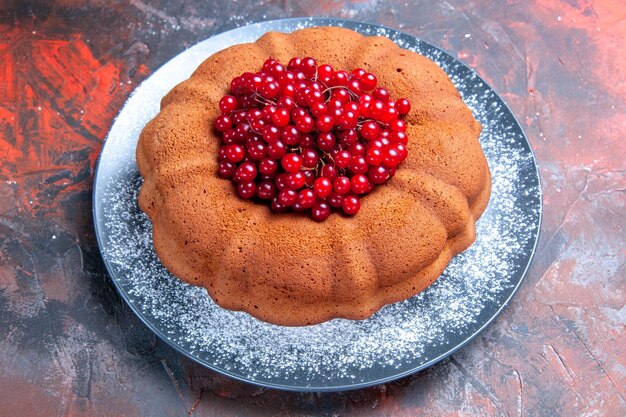 Seitliche Nahaufnahme leckerer Teller mit Kuchen und roten Johannisbeeren auf dem Tisch