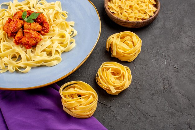 Seitliche Nahaufnahme Pasta mit Soße Schüsseln Pasta und Teller einer appetitlichen Pasta mit Soße und Fleisch auf der lila Tischdecke